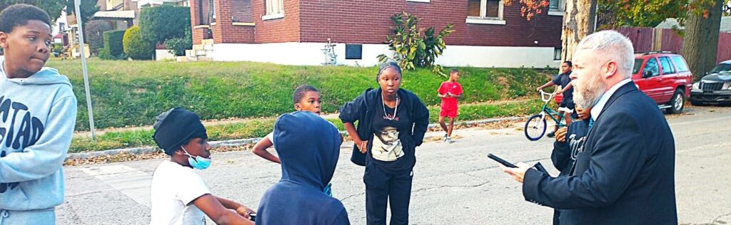 pastor joshua tapp preaching the gospel to a group of kids and teenagers on the streets of west louisville winning souls to christ